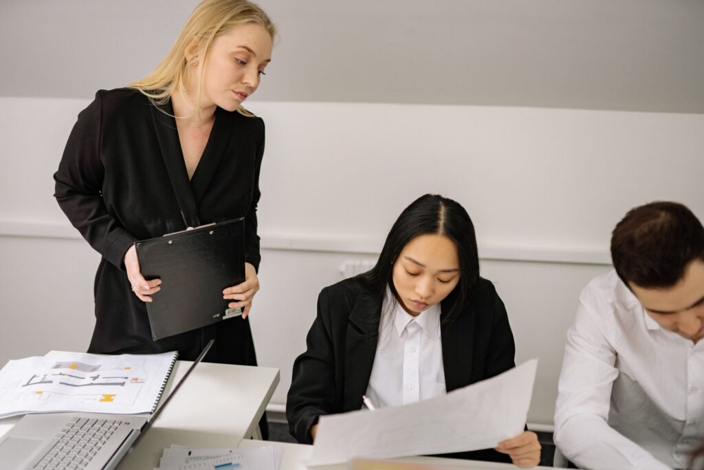 A business-suited woman addresses a group of people, conveying leadership and professionalism in a formal environment.