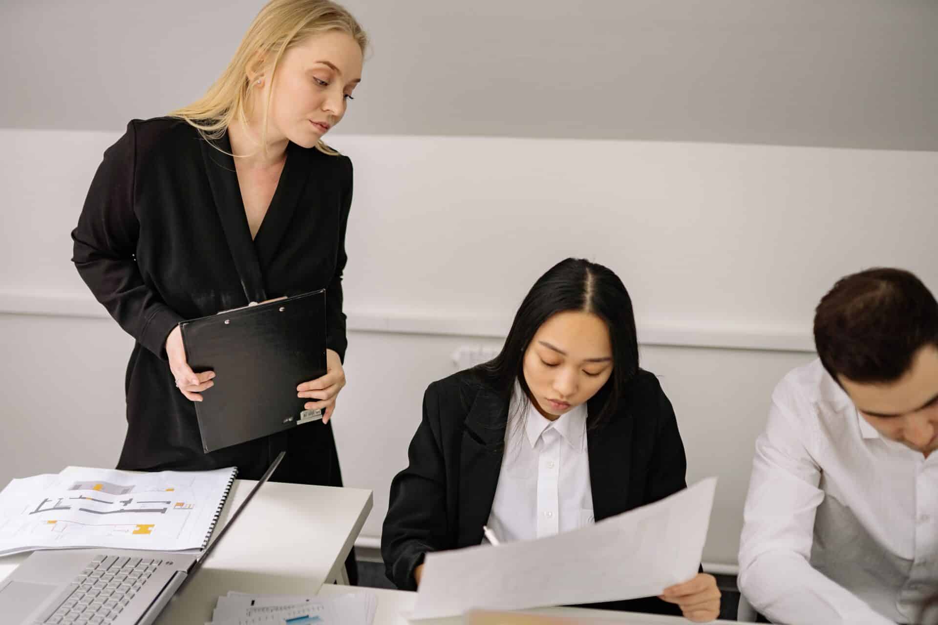 A business-suited woman addresses a group of people, conveying leadership and professionalism in a formal environment.